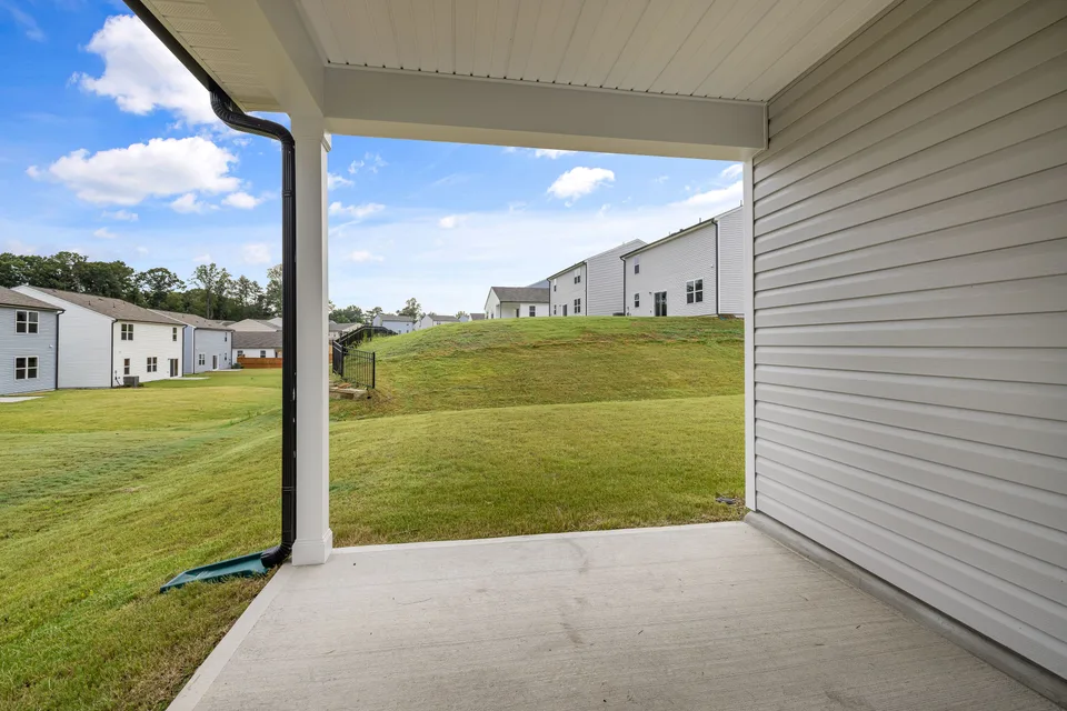 Broom-finished concrete patio beside a house and lawn